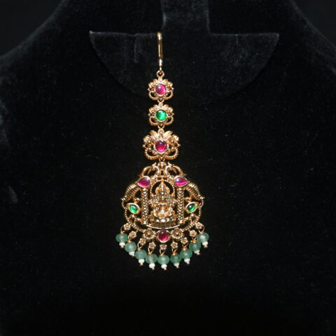 Jadau kundan Lakshmi maang tikka with green beads hanging, divine Indian accessory by Nischala Fashions.