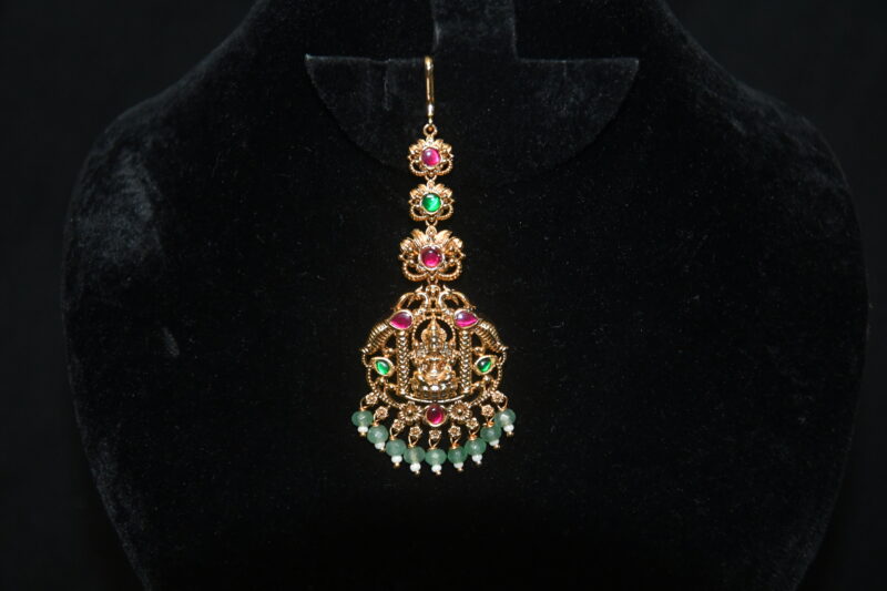 Jadau kundan Lakshmi maang tikka with green beads hanging, divine Indian accessory by Nischala Fashions.