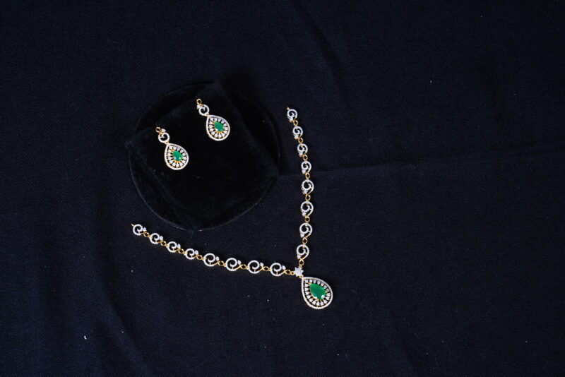 Simple diamond necklace with earrings in green, adorned with shimmering diamonds and lush green stones by Nischala Fashions.